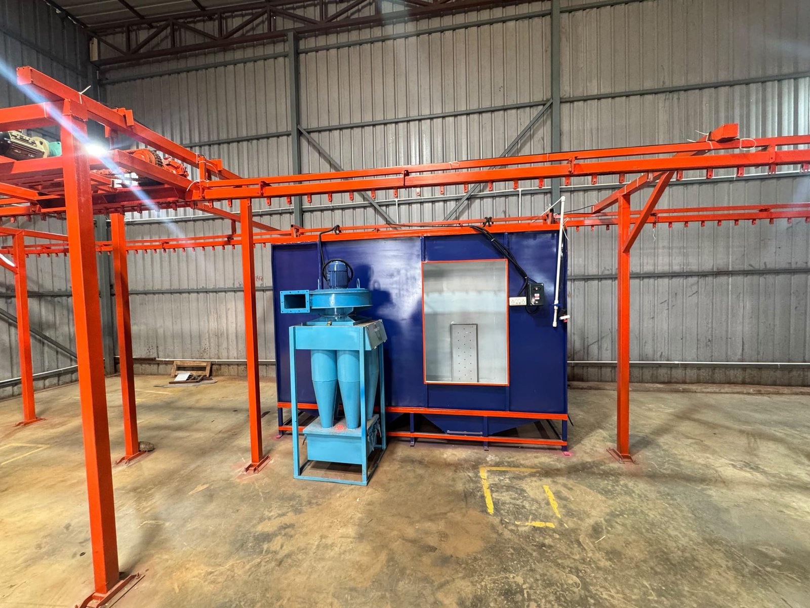 Shrinath Coatings' powder coating booth with overhead conveyor rail and cyclone powder-recovery unit