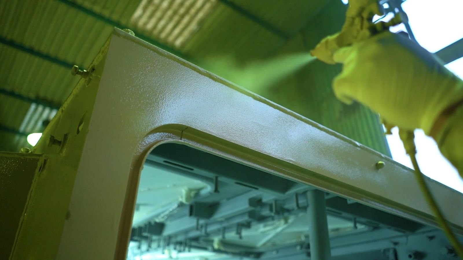 Spray gun applying an even coating to the edge of a metal component